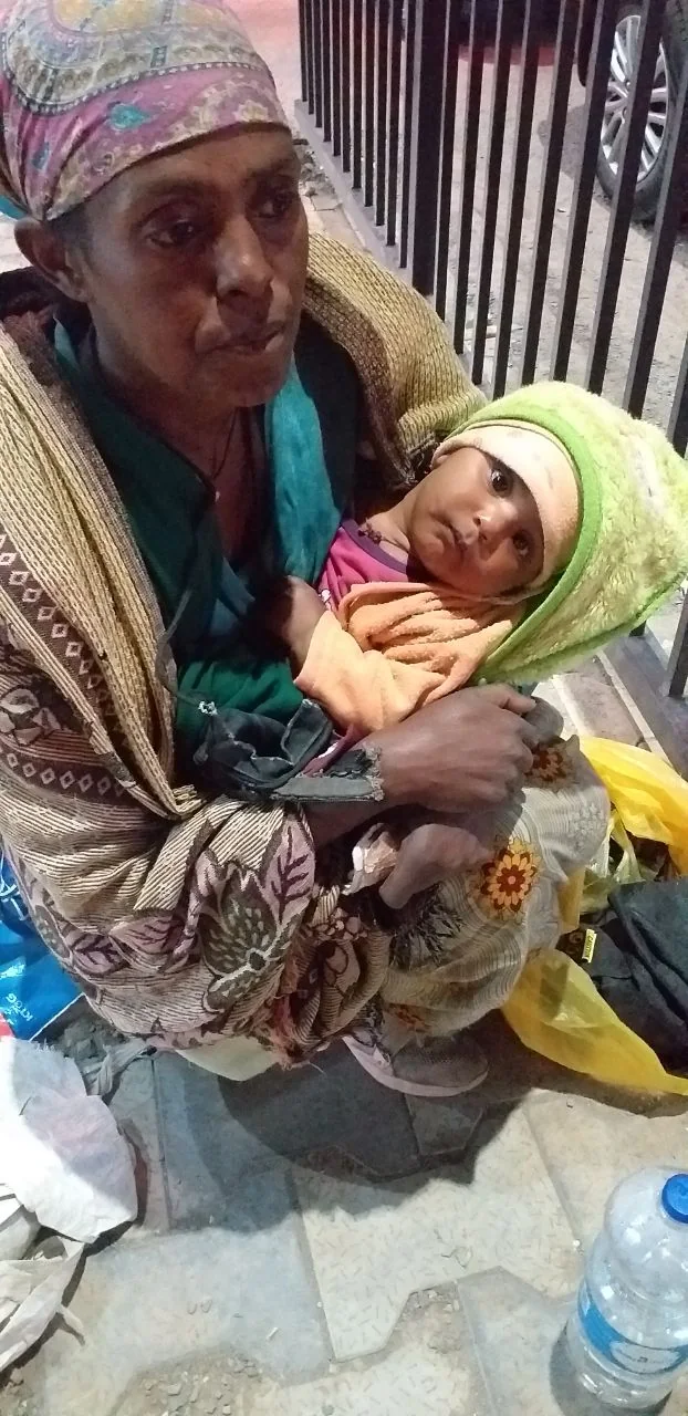 A caregiver holding a baby outdoors