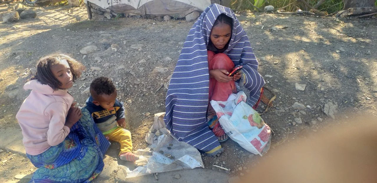 A young child helping care for a toddler while seated outdoors.