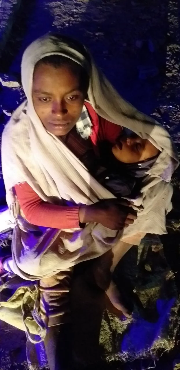 A mother holding an infant at night